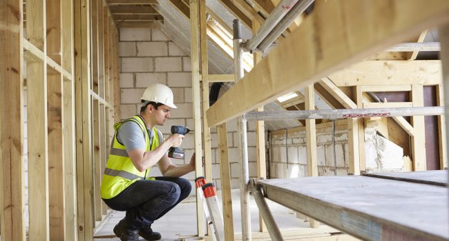 Construction Worker Using Drill On House Build