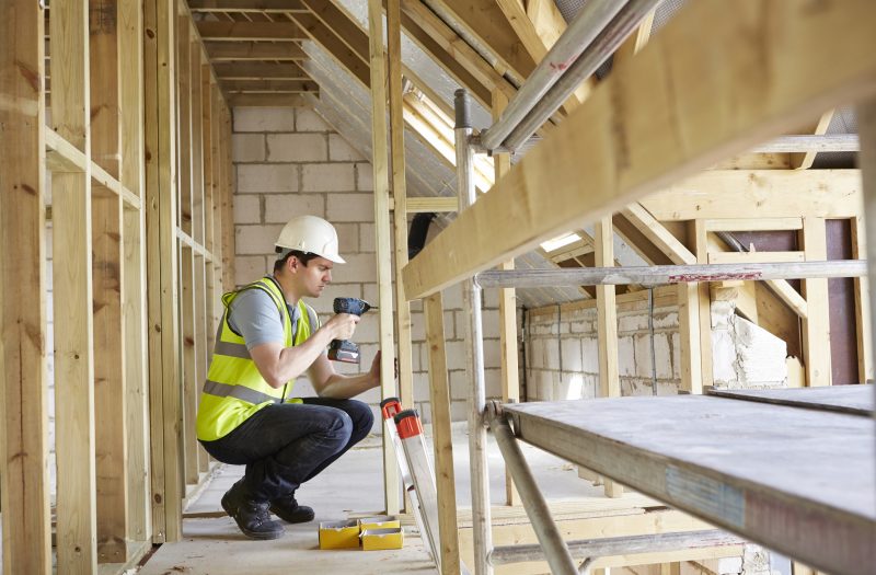 Construction Worker Using Drill On House Build